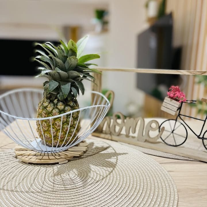 Table du studio avec un ananas dans une corbeille et la Smart TV en arrière-plan